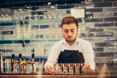Tezgahta içki ve kokteyl yapan yakışıklı bir barmen.