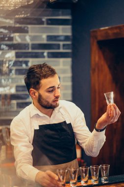 Tezgahta içki ve kokteyl yapan yakışıklı bir barmen.