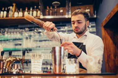 Tezgahta içki ve kokteyl yapan yakışıklı bir barmen.