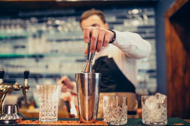 Tezgahta içki ve kokteyl yapan yakışıklı bir barmen.