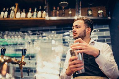 Tezgahta içki ve kokteyl yapan yakışıklı bir barmen.