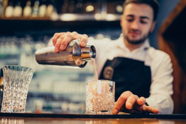 Tezgahta içki ve kokteyl yapan yakışıklı bir barmen.