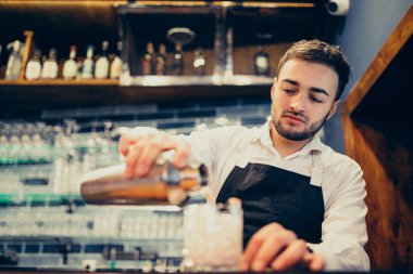 Tezgahta içki ve kokteyl yapan yakışıklı bir barmen.