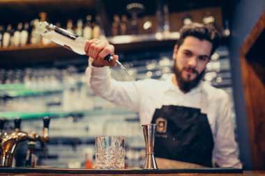 Tezgahta içki ve kokteyl yapan yakışıklı bir barmen.