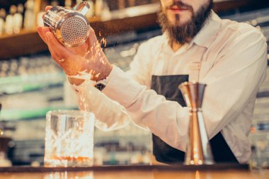 Tezgahta içki ve kokteyl yapan yakışıklı bir barmen.