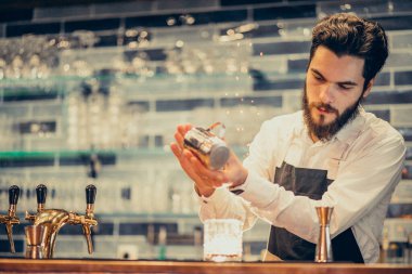 Tezgahta içki ve kokteyl yapan yakışıklı bir barmen.