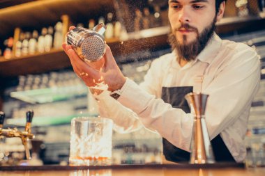 Tezgahta içki ve kokteyl yapan yakışıklı bir barmen.