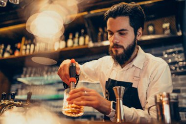 Tezgahta içki ve kokteyl yapan yakışıklı bir barmen.