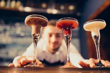 Tezgahta içki ve kokteyl yapan yakışıklı bir barmen.