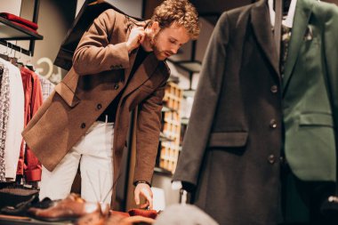 Dükkanda kıyafet seçen yakışıklı bir genç.