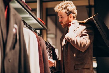 Dükkanda kıyafet seçen yakışıklı bir genç.