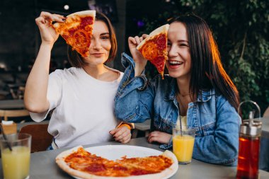 Kız arkadaşlar öğle yemeğinde barda pizza yiyorlar.