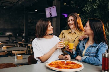 Kız arkadaşlar öğle yemeğinde barda pizza yiyorlar.