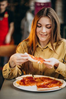 Barda pizza yiyen genç ve güzel bir kadın.