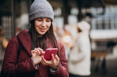 Caddenin dışında telefon kullanan ve arkadaşlarıyla buluşan bir kız.