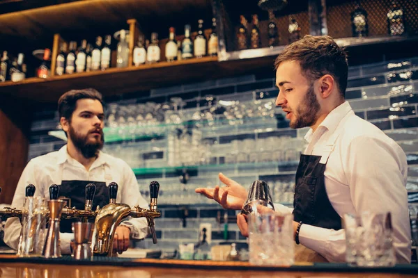 Tezgahta içki ve kokteyl yapan yakışıklı bir barmen.