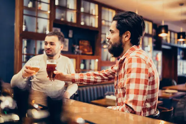 Two handsome bearded man drinking beer in pub