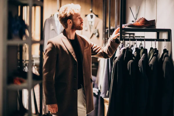 Young handsome man choosing cloth at shop