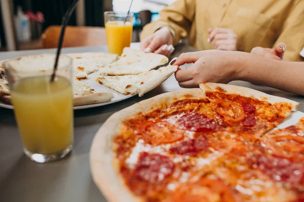 Üç kız arkadaş barda pizza yiyorlar.