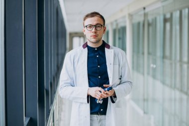 Klinikte steteskobu olan yakışıklı genç bir doktor.