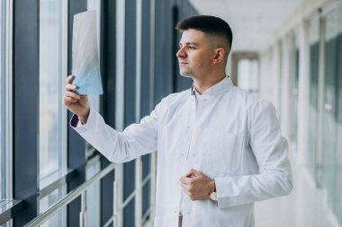 Genç yakışıklı cerrah röntgene bakıyor.