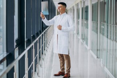 Genç yakışıklı cerrah röntgene bakıyor.