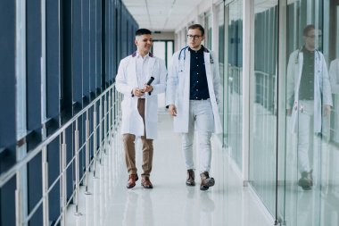 Koridorda yürüyen iki erkek doktor.