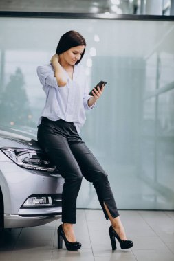 Araba galerisinde telefon kullanan genç bir kadın.