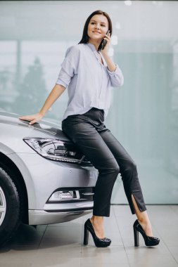 Araba galerisinde telefon kullanan genç bir kadın.