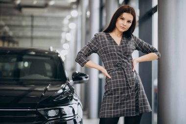 Araba galerisinde araba seçen genç bir kadın.