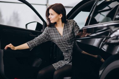 Araba galerisinde araba seçen genç bir kadın.