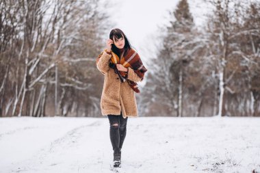 Kış parkında sıcak giysiler içinde genç mutlu bir kadın.