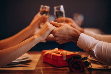 Sevgililer gününde bir restoranda el ele tutuşan ve şampanya bardakları olan çift.