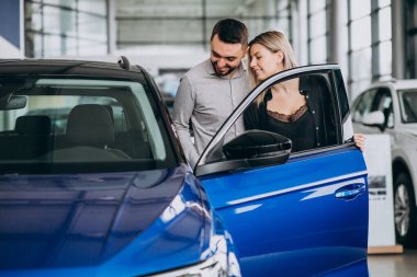 Araba galerisinde araba seçen genç bir çift.