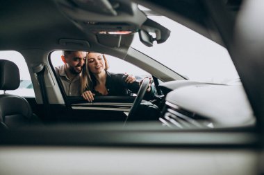 Araba galerisinde araba seçen genç bir çift.