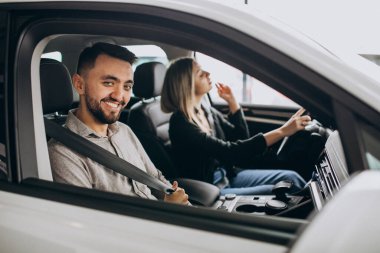 Araba galerisinde araba seçen genç bir çift.