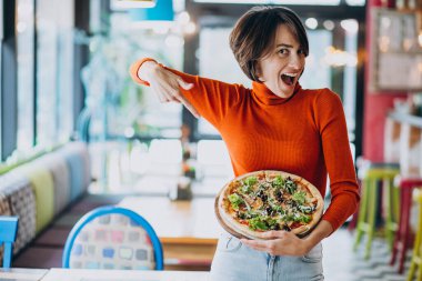 Pizzacıda pizza yiyen genç ve güzel bir kadın.