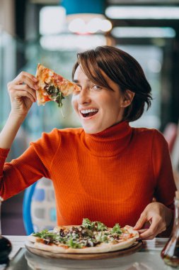 Pizzacıda pizza yiyen genç ve güzel bir kadın.