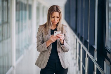 Terminalde telefon kullanan genç bir iş kadını.