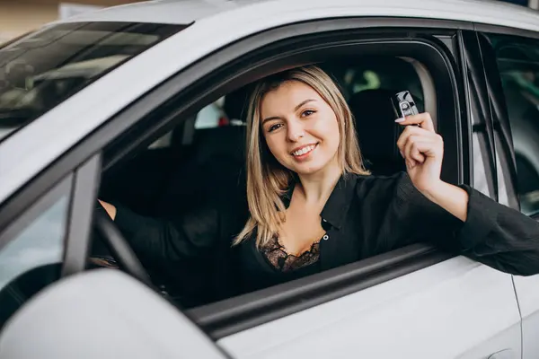 Young woman testing a car in a car showroom