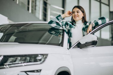 Araba galerisinde araba seçen genç bir kadın.