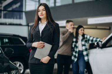 Araba galerisinde genç bir çift satış elemanıyla konuşuyor.
