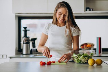 Genç bayan mutfakta salata yapıyor.