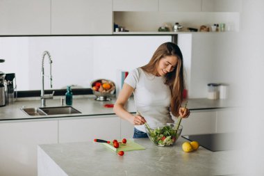 Genç bayan mutfakta salata yapıyor.