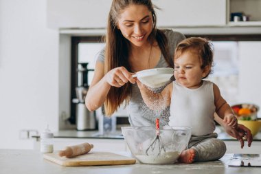Genç anne ve küçük oğlu mutfakta yemek pişiriyor.
