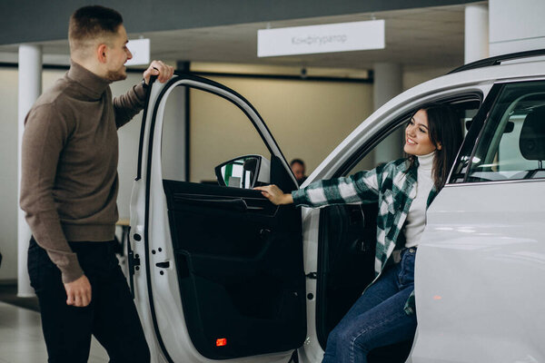 Молодая пара выбирает машину в автосалоне