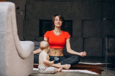 Evde yoga yapan küçük oğlu olan genç bir anne.