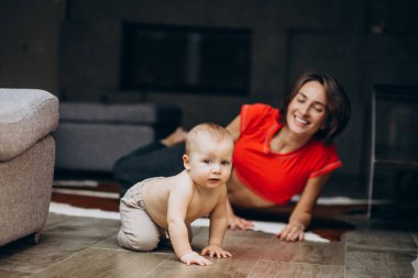 Evde yoga yapan küçük oğlu olan genç bir anne.