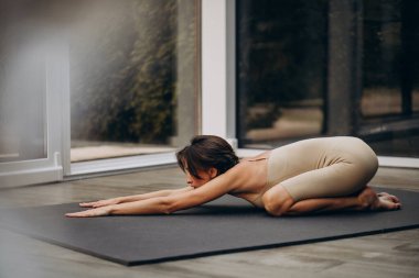 Evde yoga yapan genç bir kadın.