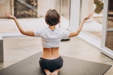 Evde yoga yapan genç bir kadın.
